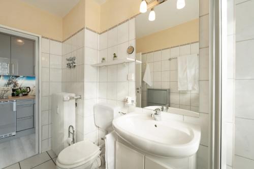a white bathroom with a sink and a toilet at Steffi s Vogelnest in Scharbeutz