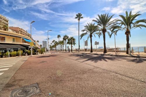 une rue vide avec des palmiers et la plage dans l'établissement Appartement proche des Plages et du Palais, à Cannes
