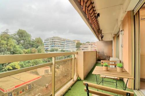 - un balcon avec une table et des bancs dans un bâtiment dans l'établissement Appartement proche des Plages et du Palais, à Cannes