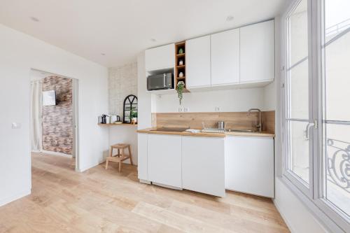 une cuisine avec des armoires blanches et un évier dans l'établissement JO 2024 - Face au métro 13 - 26 m2 refait à neuf, à Saint-Ouen