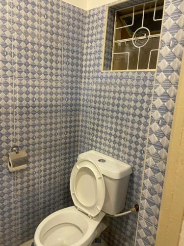 Łazienka z toaletą i niebieskimi ścianami wyłożonymi kafelkami w obiekcie Sanrod Hotel Maua w mieście Maua