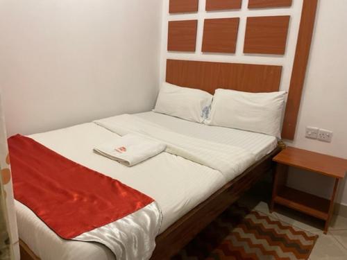 Una cama en una habitación con una manta roja. en Sanrod Hotel Maua, en Maua
