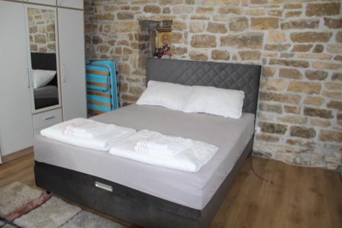 Kod Mladena في Buković: سرير في غرفة بجدار من الطوب