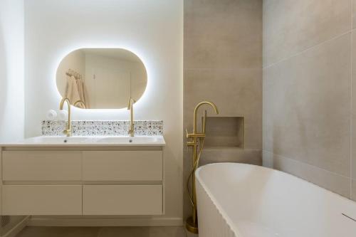 La salle de bains est pourvue d'une baignoire blanche et d'un miroir. dans l'établissement L’écrin de douceur pour 4/6 personnes + parking privé, à Courbevoie