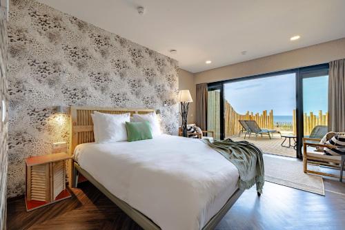 a bedroom with a large bed and a balcony at Beachhouse Hotel in Zandvoort