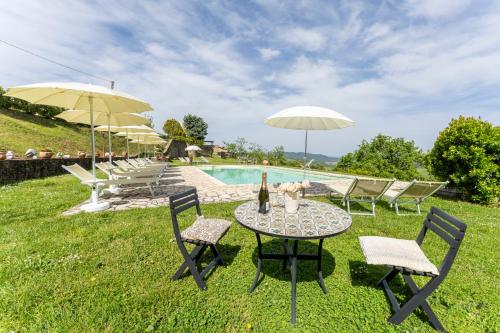 a table and chairs with umbrellas and a pool at Podere Marcigliana in Radicondoli