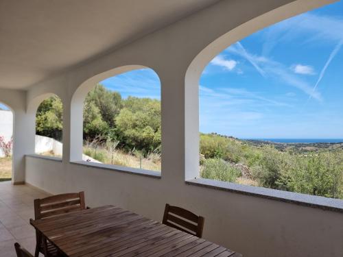 Un comedor con una mesa y dos ventanas. en Villa Lu Tizzoni, en Budoni