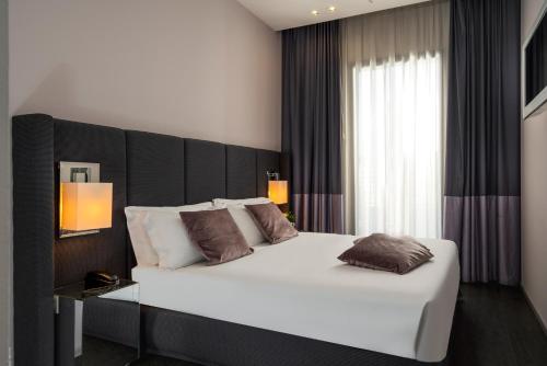 a bedroom with a large white bed with a black headboard at Hotel Ines in Cattolica