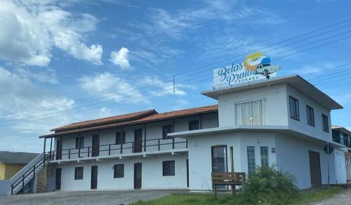 a white building with a sign on top of it at Pousada Belas Praia quarto Praia da Vila in Imbituba