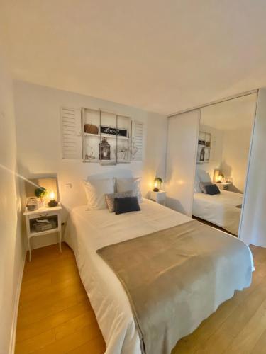 a white bedroom with a large bed and a mirror at La PASSERELLE in Toulouse