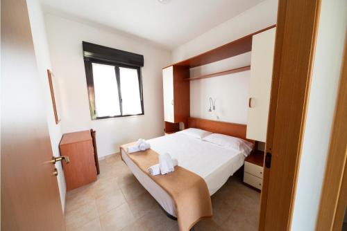 a bedroom with a white bed and a window at Villaggio Diomedea in Campomarino
