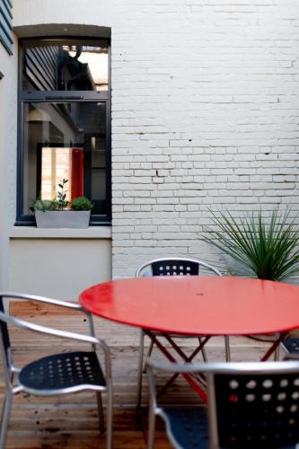 une table et des chaises rouges devant un mur de briques dans l'établissement Le 5 - maison de style centre ville Normandie, à Eu