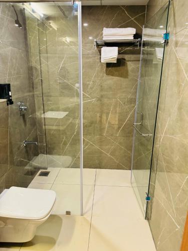 a shower with a toilet and a glass shower door at Hotel Park Royal in Dwarka