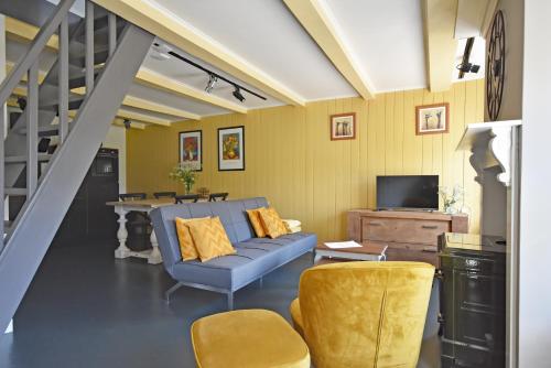 een woonkamer met een blauwe bank en gele stoelen bij EAstay appartement 2 in Oostermeer