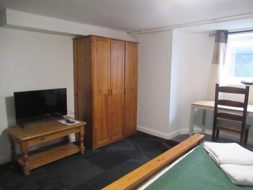 a living room with a tv and a wooden cabinet at Captain Howey Hotel in New Romney