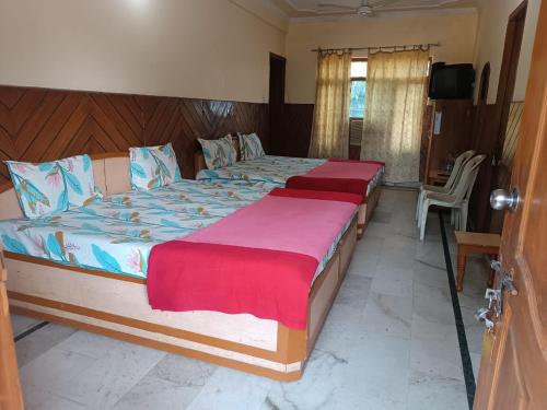 two twin beds in a bedroom with a tv at Hotel Rajpal Guest House in Dehradun