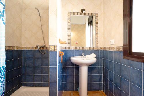 een blauwe betegelde badkamer met een wastafel en een douche bij Casa Juan Solo Familias in Cádiz