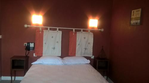 a bedroom with a bed with two lights on the wall at Hôtel Restaurant Le Moulin de la Renne Adults Only proche Zoo de Beauval in Thésée