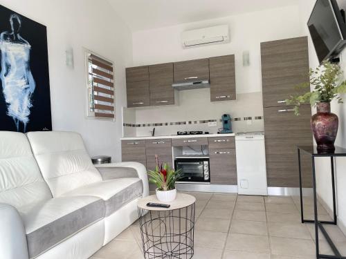 a living room with a white couch and a kitchen at Maisonnette au calme in Montauroux