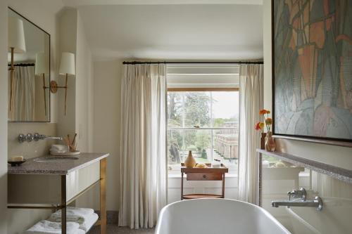 uma casa de banho com uma banheira, um lavatório e uma janela em The Grove em Chandler's Cross