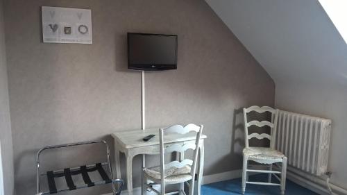 a room with two chairs and a tv on the wall at Hôtel Restaurant Le Moulin de la Renne Adults Only proche Zoo de Beauval in Thésée