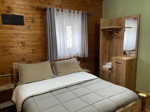 1 dormitorio con 1 cama con pared de madera en 'Gurra Family' Guesthouse, en Theth