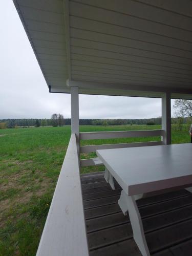 a white picnic table on a porch with a field at Okno Na Puszczę in Werstok