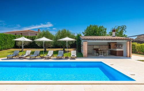 una piscina in un cortile con sedie e ombrelloni di Rustic Villa Peran with outdoor pool in Tinjan a Radetići