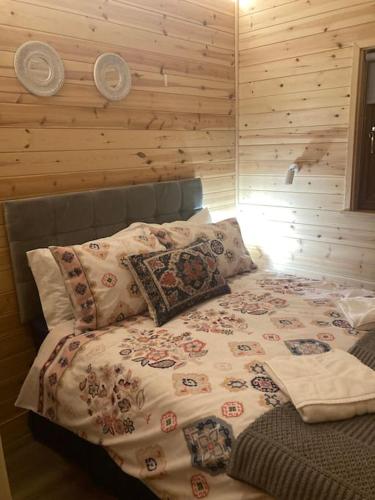 a bed in a bedroom with a wooden wall at Eco-friendly Cabins Cabin 1 in Norton Disney