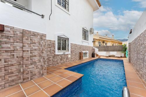 a pool in the backyard of a house with a stone wall at Casa Ohana Fuengirola in Fuengirola