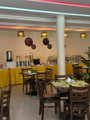 a dining room with tables and chairs and a kitchen at Aron International Hotel in Juba