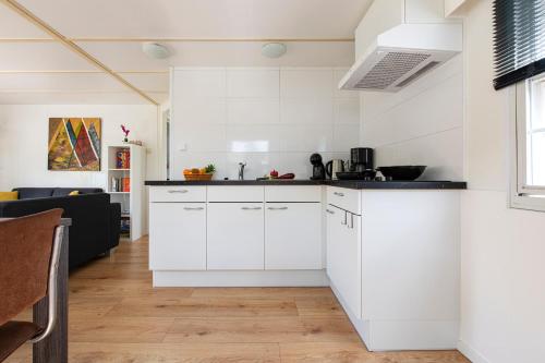 a kitchen with white cabinets and a living room at 75, Relax - Nature - Cycling - Hiking - Central! - Leisure only in Oisterwijk