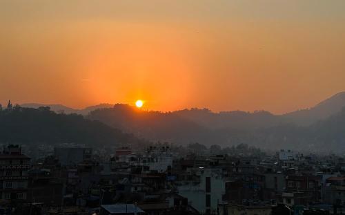 a view of a city with the setting sun at Yog Hostel- Rooftop Yoga & Backpacker Social Stay in Thamel, Kathamndu in Kathmandu