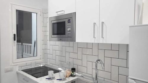 une cuisine blanche avec un évier et un micro-ondes dans l'établissement PAKITO TENERIFE Mareverde, à Adeje