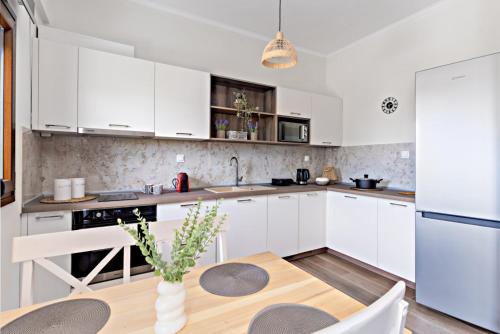 una cucina con mobili bianchi e un tavolo di legno di MARY DUKE apartment a Nikiti