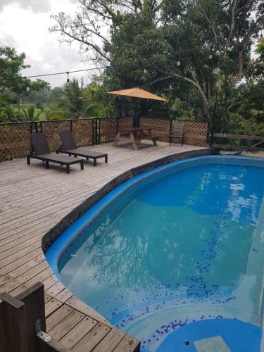 a swimming pool with a picnic table and an umbrella at Rainforest Lodge del Rio in Portobelo