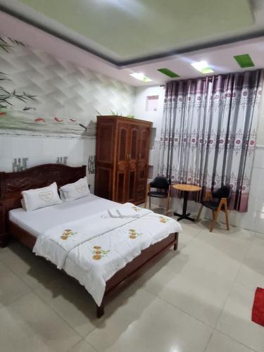 a bedroom with a large bed and a table and chairs at Khách Sạn Trường Thịnh in Ben Tre