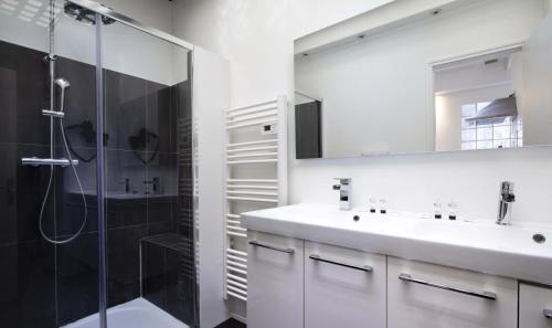 biała łazienka z prysznicem i umywalką w obiekcie Hôtel de la Gaîté w Paryżu