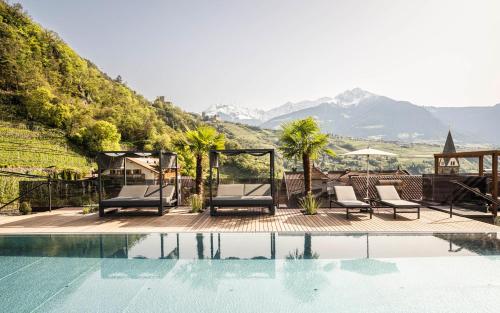 a pool with chairs and mountains in the background at Hotel Kassian in Lagundo