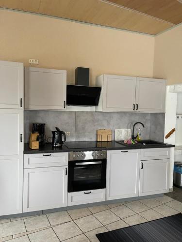 a kitchen with white cabinets and a stove top oven at Großes Familienapartment mitten in der Natur in Neu Gaarz