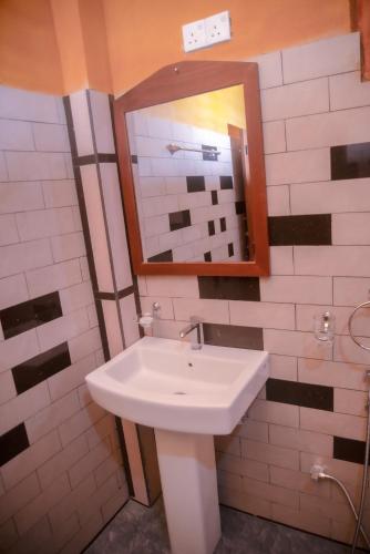 a bathroom with a white sink and a mirror at Sinharaja Riverside in Deniyaya