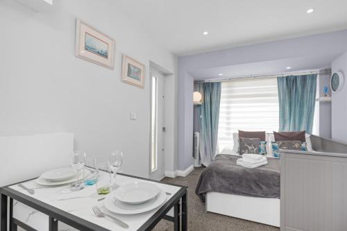 a bedroom with a bed and a table with plates and wine glasses at Rottingdean Boutique Studio Apartment By The Sea in Rottingdean