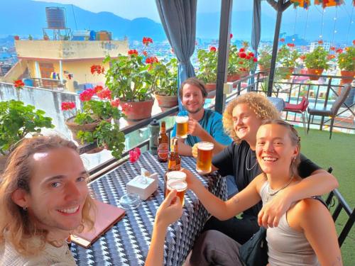 a group of people sitting at a table drinking beer at Yog Hostel in Kathmandu