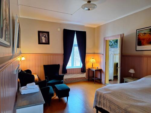 a hotel room with a bed and chairs and a window at Tjøtta Gjestegaard in Alstahaug