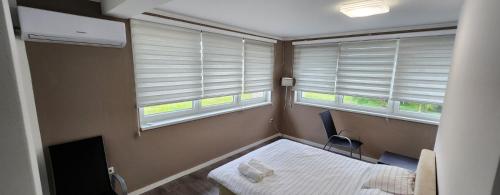 a room with two windows and a bed and a chair at Urban villa in Sarajevo