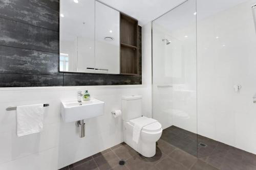 a white bathroom with a toilet and a sink at Chatswood CBD 2BR l Balcony l Parking l Office in Sydney