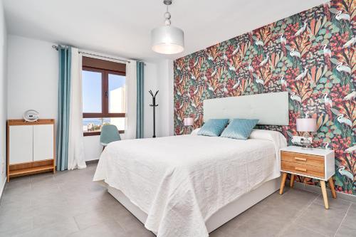 een slaapkamer met een groot bed met bloemenbehang bij El ático del Oasis in Salobreña