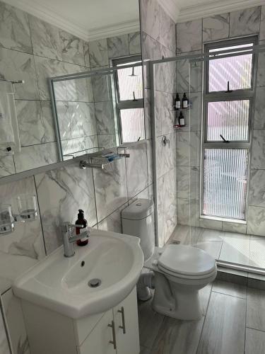 a white bathroom with a sink and a toilet at The Villa Rosa Hotel & Self-catering Apartments in Cape Town