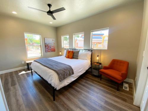 a bedroom with a bed and a chair and windows at Timber & Tin G 2Bed 2Bath w Pool & Rooftop Deck in Kanab