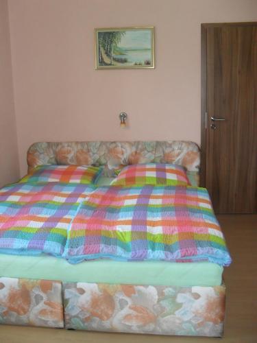 a bed with a colorful comforter and two pillows at Pension Rak in Karlovy Vary